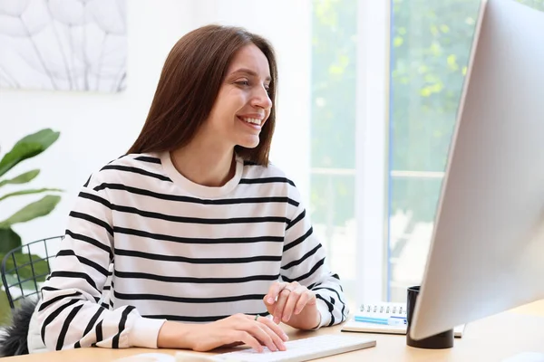 İçerideki ahşap masada bilgisayar kullanan kadın. Ev işyeri