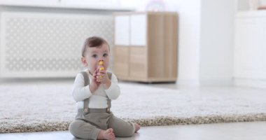 Evinde yerde oyuncağı olan şirin bir bebek.