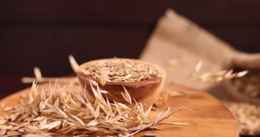 Kase içinde yulaf taneleri ve tahta üzerinde çiçekler, yakın plan.