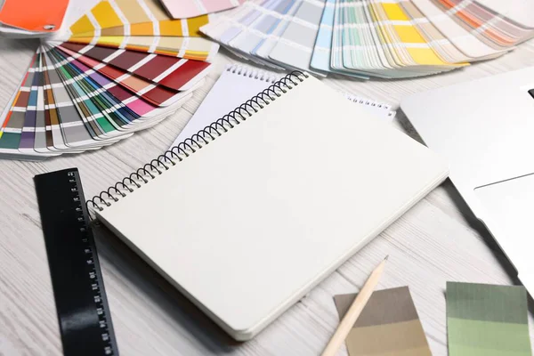 Beyaz ahşap masa üzerindeki boş çizim defteri ve kırtasiye malzemesi, yakın plan.