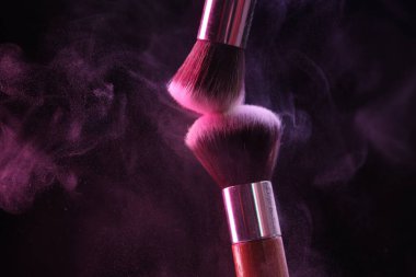 Renkli göz gölgeli makyaj fırçaları siyah arka planda neon ışıkları, yakın plan. Metin için boşluk