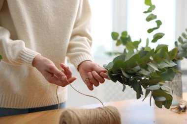 Çiçekçi dükkanındaki ahşap masada güzel okaliptüs dalları yapan bir makara ipliği olan çiçekçi.