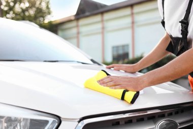 Kaputu sarı mikrofiber bez ile silen adam, yakın plan.