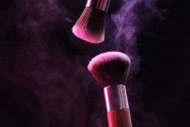 Renkli göz gölgeli makyaj fırçaları siyah arka planda neon ışıkları, yakın plan