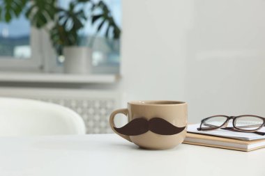 Babalar Günün kutlu olsun. Kağıt bıyıklı fincan, kitaplar ve gözlükler beyaz masa içinde, mesaj için yer var.