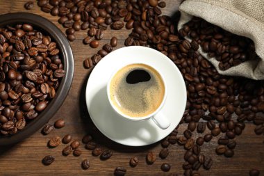 Aromatik kahve fincanda ve fasulye ahşap masada, düz yerde.