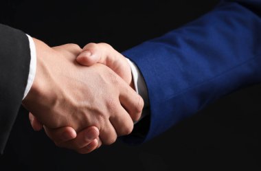 İş ortakları siyah arkaplanda el sıkışıyor, yakın plan