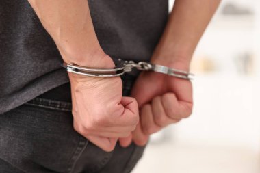 Bulanık ışıklı arka planda metal kelepçeli adam, yakın plan.