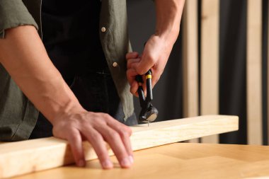 Kapalı alanda kıskaçlarla tahta çiviyi söken adam, yakın plan.