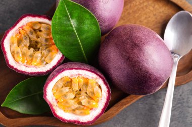 Taze tutku meyveleri ve yeşil yapraklar gri masada, üst manzara