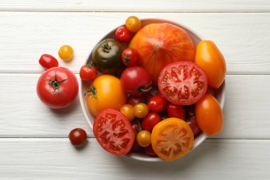 Beyaz ahşap masa üzerinde birçok farklı olgun domates, üst görünüm