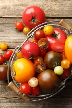 Tahta masada, sepetin içinde farklı olgun domatesler.