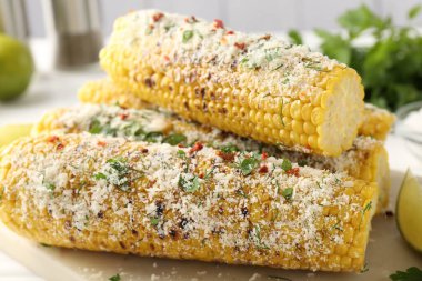 Beyaz masada maydanozlu ve peynirli mısır koçanları, yakın plan.