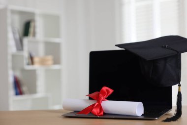 Mezuniyet şapkası, dizüstü bilgisayar ve diploma kapalı masa, yakın plan. Metin için boşluk