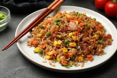 Gri masada servis edilen sebzeli ve jambonlu leziz pilav. Yakın plan.