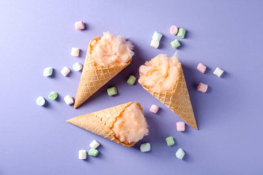 Waffle külahında pamuk şeker ve menekşe arka planda marşmelov.