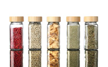 Ayna yüzeyindeki kavanozlarda beyaz arka plana karşı çok farklı aromatik baharatlar var.