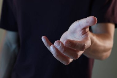 Gri arkaplanda bir şey tutan adam, yakın plan.