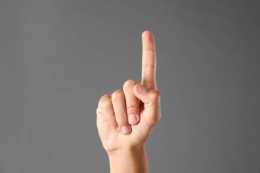 Adam gri arkaplanda bir şeye dokunuyor, yakın plan.