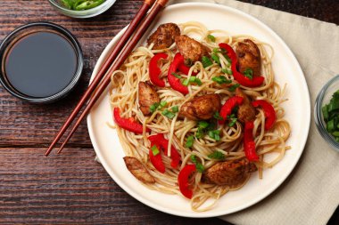 Tavuk, yeşil soğan ve sebzeli erişte ahşap masada servis edilir.