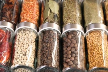 Arka plan olarak cam kavanozlardaki farklı baharatlar, yakın plan