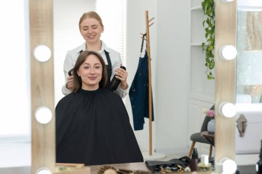 Profesyonel kuaför müşteriyle kuaförde çalışıyor.