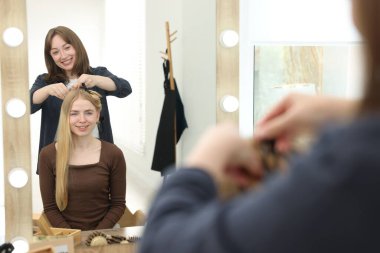 Profesyonel kuaför müşteriyle kuaförde çalışıyor.