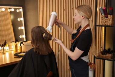 Kuaför kuaförde müşterinin saçını kurutuyor.