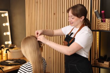 Profesyonel kuaför müşteriyle kuaförde çalışıyor.