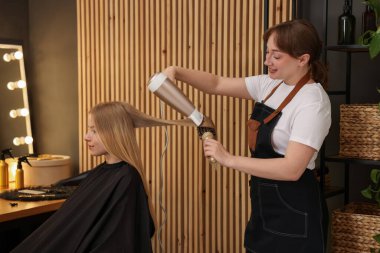 Kuaför kuaförde müşterinin saçını kurutuyor.