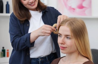 Profesyonel kuaför müşteriyle kuaförde çalışıyor.