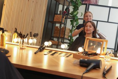 Kuaför kuaförde müşterinin saçını kurutuyor.