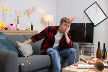 Adam partiden sonra dağınık bir odada kanepede akşamdan kalma.