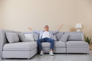 Evdeki kanepede dinlenen genç adam.