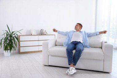 Evdeki kanepede dinlenen genç adam.