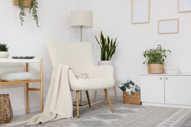 Şık koltuk, lamba, dolap, konsol masası ve oda çiçekleri. İç tasarım