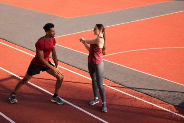 Stadyumda koşmadan önce ısınma egzersizleri yapan gülümseyen bir çift. Metin için boşluk
