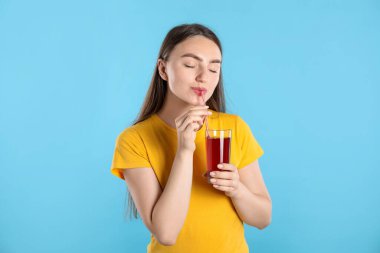 Açık mavi arka planda samandan meyve suyu içen kadın