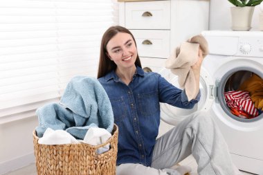Çamaşır makinesinin yanında çamaşır makinesi olan bir kadın.