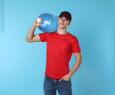 Açık mavi arka planda serin su şişesiyle teslimatçı.