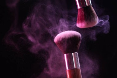 Renkli göz gölgeli makyaj fırçaları siyah arka planda neon ışıkları, yakın plan. Metin için boşluk