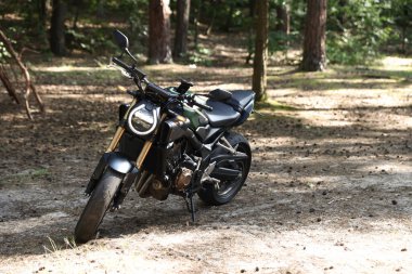 Ormana park edilmiş modern siyah bir motosiklet.