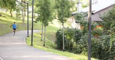 Spor kıyafetleri içinde yakışıklı bir adam dışarıda koşuyor. Sağlıklı yaşam tarzı