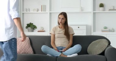 Endişeli genç kadın hamilelik testini evde kocasına gösteriyor.