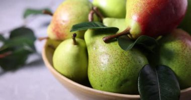 Taze armutlar ve yeşil yapraklar masada, yakın plan.