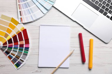 Boş eskiz defteri, dizüstü bilgisayar ve kırtasiye malzemesi beyaz ahşap masa, düz yatıyordu.