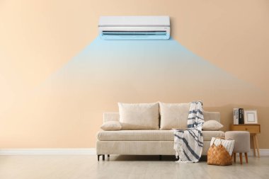 Yastıklı kanepe, battaniye, puf ve odada resim. Klima içeride rahat bir sıcaklık sağlıyor.