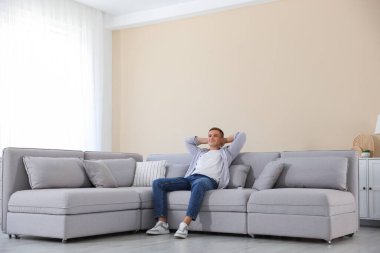 Evdeki kanepede dinlenen genç adam.