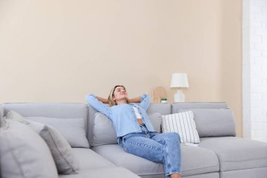 Evdeki kanepede dinlenen güzel bir kadın.