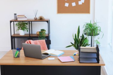 Ev çalışma alanı. Modern laptop ve kırtasiye malzemeleri ahşap masa içinde.